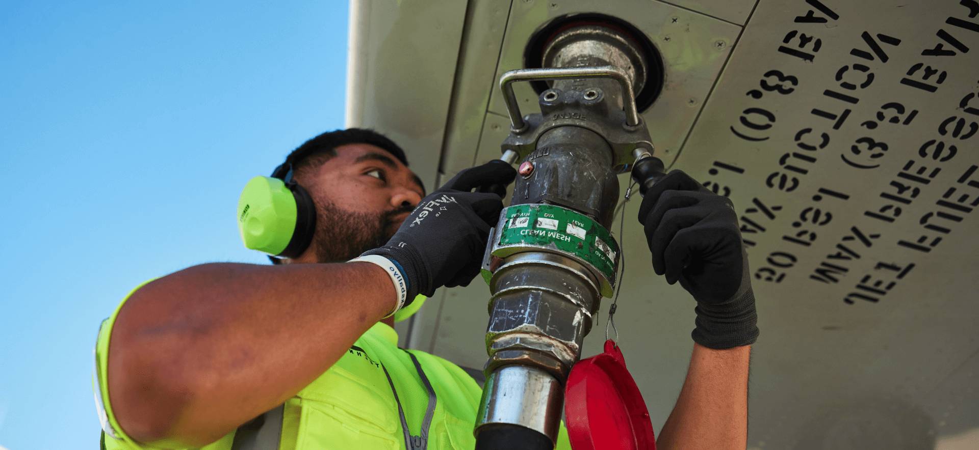 A man is fueling a plane with a hose attached to it.